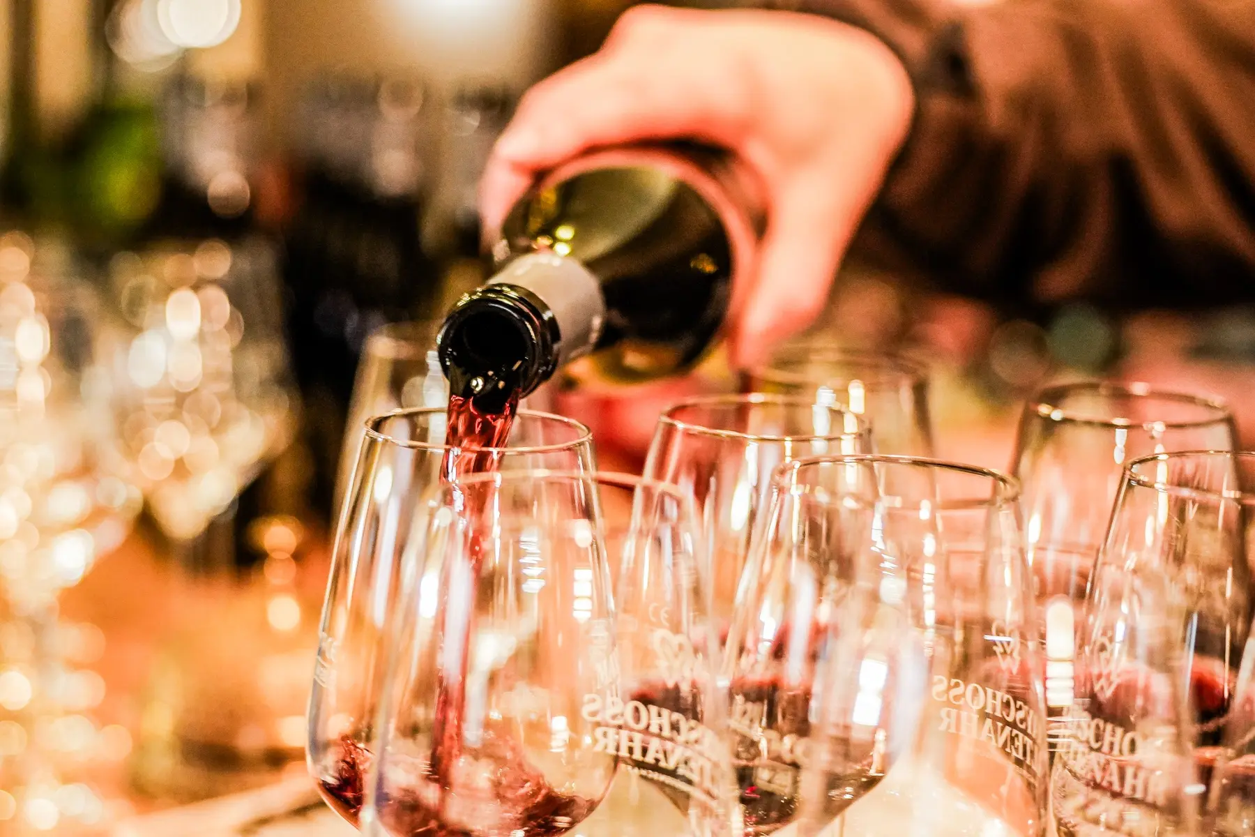 Rotwein wird bei einer Weinprobe in mehrere Gläser eingeschenkt